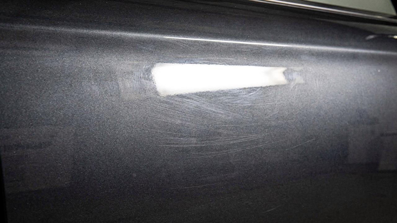 Grey door panel before correction, swirl marks visible under studio light